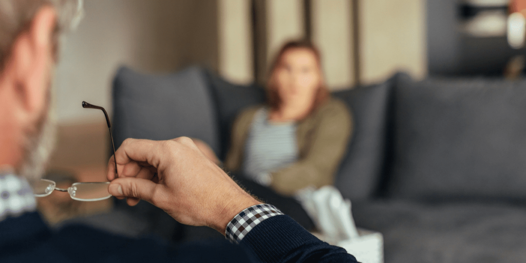 a therapist takes their glasses off while looking at a patient